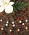 Floating Freshwater Pearls in white, black, and coral colors displayed on a hardwood table with a white plumeria flower and fern accent