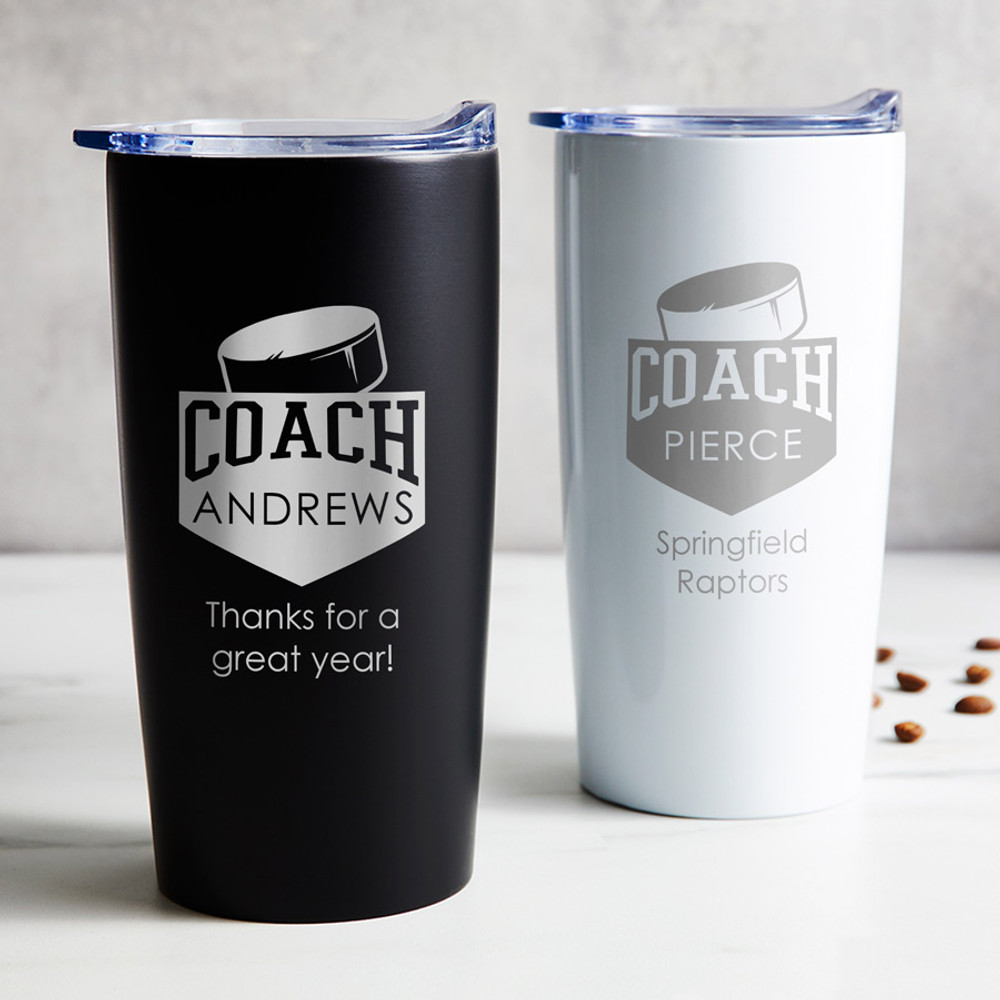 Personalized Hockey Coach stainless steel coffee tumbler in black or white laser engraved with hockey design, coach's name, and your special message, displayed on table.