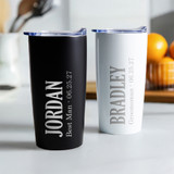 Personalized Groomsman stainless steel coffee tumbler in black or white laser engraved with their name, wedding role, and wedding date, displayed on table. Personalized Groomsman stainless steel coffee tumbler in black or white laser engraved with their name, wedding role, and wedding date, displayed on table.