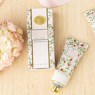 Flat lay of botanical berry hand cream with pink packaging, green vines and strawberry bud design