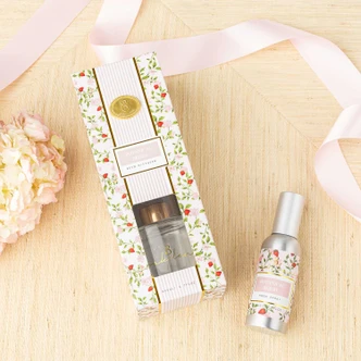 Flat lay of botanical berry room spray with pink floral packaging, green vines and strawberry bud design