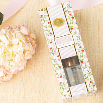 Flat lay of botanical berry diffuser with strawberry bud print, green vines and fragrance oil bottle