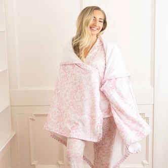 Woman wrapped in pink bow print plush throw blanket showing cozy drape and size