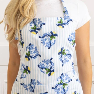 Woman wearing the Holiday Chinoiserie cotton apron with a blue floral and striped print (alternate angle)