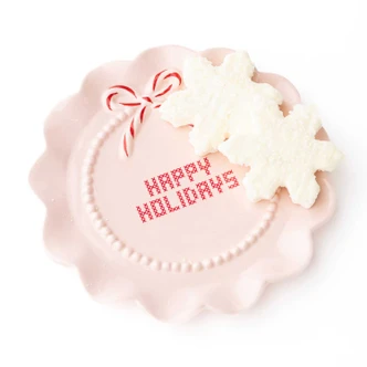 Blush pink ceramic dessert plate with 'Happy Holidays' lettering and a peppermint bow (alternate angle)