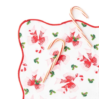 Holly Jolly Bows scalloped dinner napkin with a red trim and pink and red bow print (alternate angle)