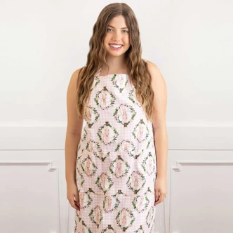 Woman wearing the Sugarplum Gingham cotton apron with a pink gingham and nutcracker wreath print