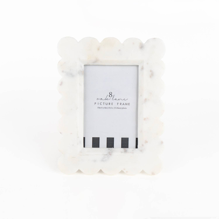 White marble picture frame with a scalloped edge and easel back holding a 4x6 photo