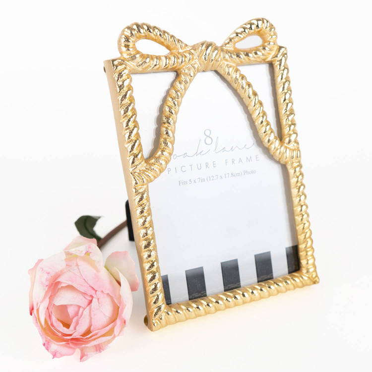 Gold-tone picture frame shaped like a wrapped ribbon with a bow at the top
