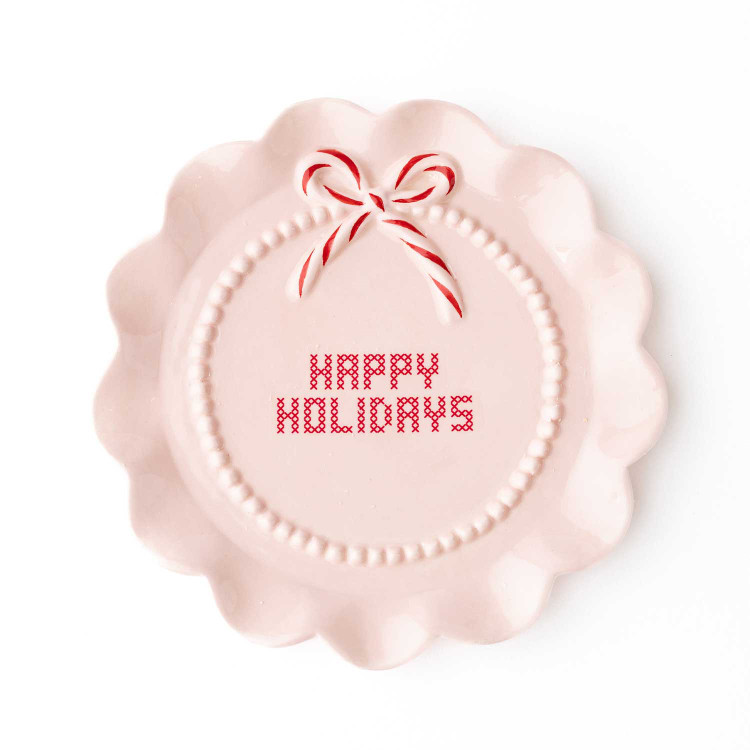 Blush pink ceramic dessert plate with 'Happy Holidays' lettering and a peppermint bow