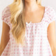 Close-up of pink gingham cotton fabric with strawberry bud print and ruffle neckline detail