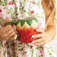 Woman holding strawberry-shaped coffee mug with glossy finish and hand-painted detail (lifestyle view)