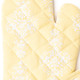 Close-up of golden damask oven mitt fabric with quilted stitching and soft yellow tone