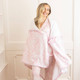 Woman wrapped in pink bow print plush throw blanket showing cozy drape and size