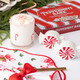 Clear drinking glass with candy cane bead icons, filled with a festive holiday drink (styled detail view)