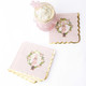 Pink gingham paper beverage napkin with a nutcracker in a floral wreath and gold scalloped edge (styled detail view)