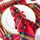 Red tartan plaid cotton dinner napkin tied with a red ribbon (shown in a styled setting)