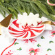 Ceramic dessert plate shaped like a red and white swirled peppermint candy, holding snowflake cookies (alternate angle)