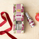 Pomegranate & Oud reed diffuser with a glass vessel, gold collar, and reeds in a striped gift box (styled detail view)