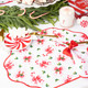 Holly Jolly Bows scalloped dinner napkin with a red trim and pink and red bow print (styled detail view)