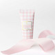 Frosted Sugarplum travel hand cream tube in a pink gingham nutcracker print (styled detail view)