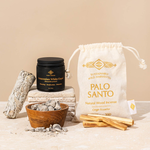Smudging sampler with Amazonian white copal resin, white sage smudge stick, and Ecuadorian palo santo sticks displayed on white rocks