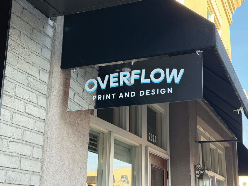 Front view of a mirrored hanging sign with vibrant colored lettering on the reflective surface.