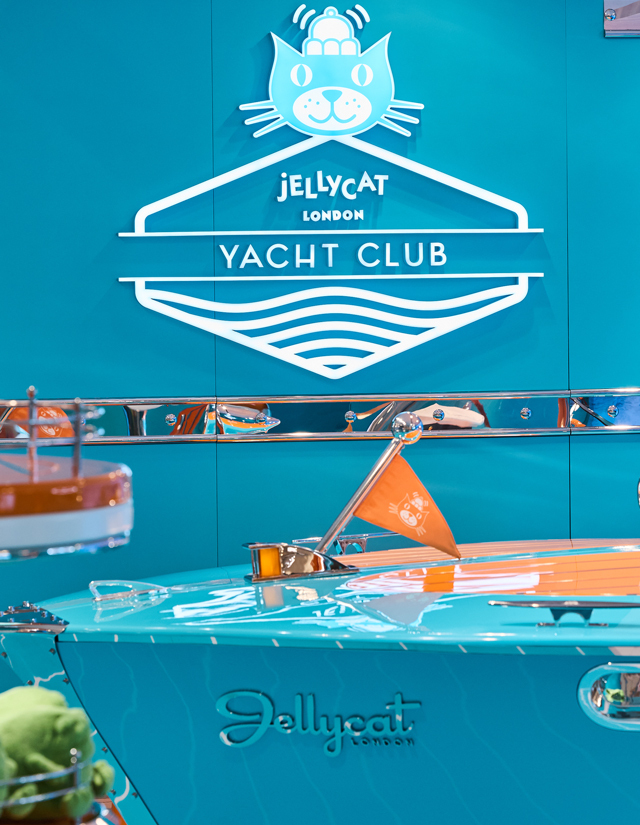 Enseigne Jellycat Yacht Club au-dessus d’une décoration sur le thème d’un bateau turquoise, agrémentée d’un drapeau orange.