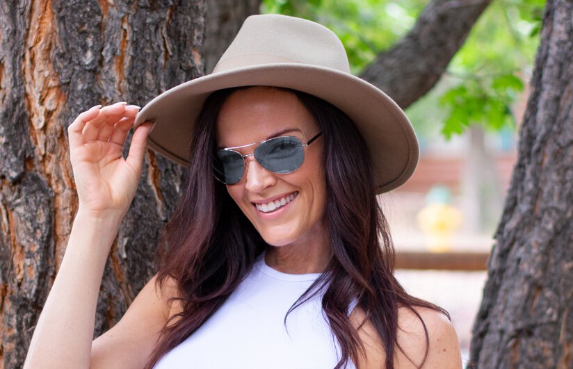 Young woman in hat wearing TheraSpecs Z-Blue lenses in Pilot style