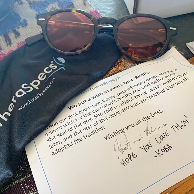 Photo of TheraSpecs unboxed with glasses, wish note and microfiber bag