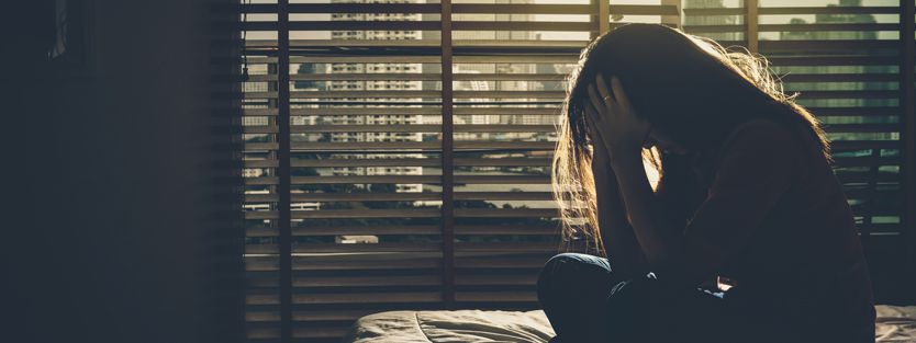 Link Between Light and Sound Sensitivity Woman in dark room with photophobia and phonophobia