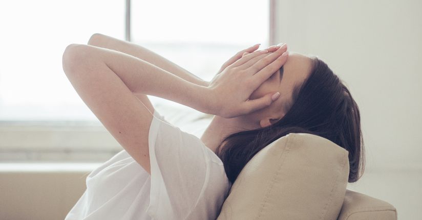 Woman holding her eyes over head from photophobia