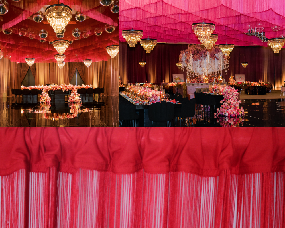 Luxury Red String Fringe Ceiling Installation with Chandeliers — Elegant Immersive Event Décor A glamorous event space featuring a ceiling fully draped in rich red string fringe curtains, creating a soft wave-like texture overhead. Crystal chandeliers and disco balls hang between the flowing strands, casting warm, elegant lighting throughout the room. Below, banquet tables are decorated with lush pink and red floral arrangements and candlelight, set against glossy black flooring and soft gold wall drapes. The lower portion of the image shows a detailed close-up of the red string fringe curtain header and strands.