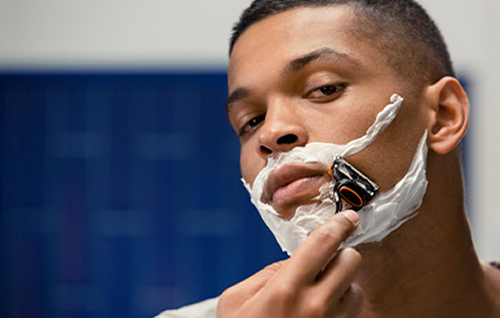 Close‑up of a razor shaving facial hair along the neck and jawline, illustrating prevention of razor bumps and ingrown hairs