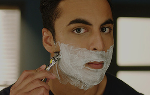 Man shaving facial hair along the jawline using a razor as part of a step‑by‑step face shaving routine