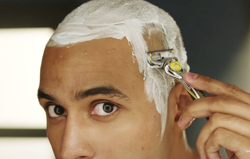 A Man with Razor shaving the scalp with shaving cream for a smooth bald finish