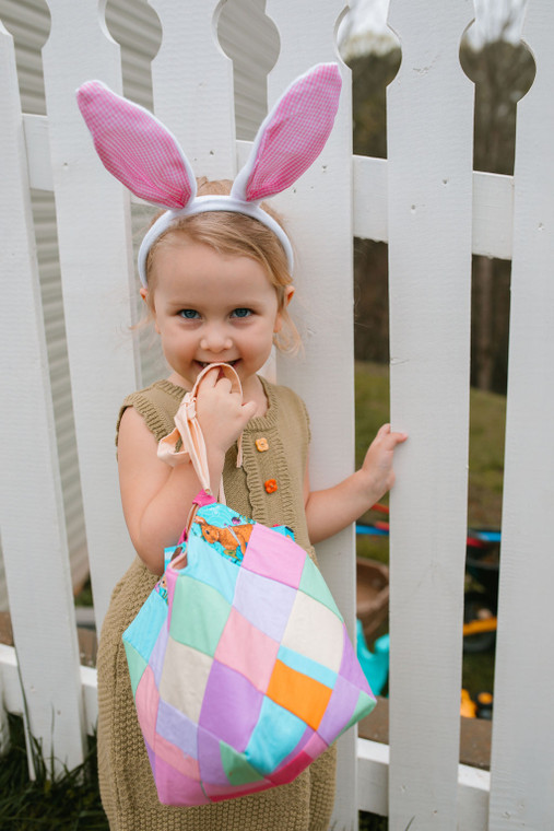 Adorable little girl in bunny ears using a Bitty Bag for an egg hunt