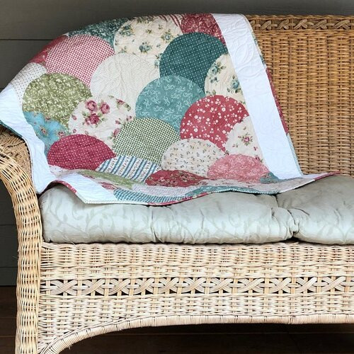 Finished clamshell quilt in pinks and greens over the back of a couch