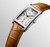 Longines DolceVita watch, rectangular stainless steel case with silver dial and blue hands, brown leather strap with alligator pattern, automatic movement, date display at 6 o'clock.