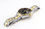 Roamer Watch, luxury men's wristwatch with stainless steel and gold two-tone bracelet, black dial, and rotating bezel with gold accents.