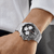 BREITLING Chronomat B01 42 [AB0134101B1A1], a luxury stainless steel wristwatch with a black dial, chronograph subdials, and a fold-over clasp bracelet on a man's wrist.