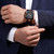 CERRUTI 1881 WATCH, a luxury men's wristwatch with a black dial and rose gold accents worn on a wrist with a black strap.