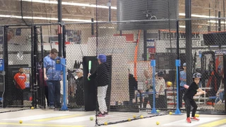 A parent and youth baseball player loading a BSG Cage Card before winter batting practice at Burghardt Sporting Goods in New Berlin, Wisconsin
