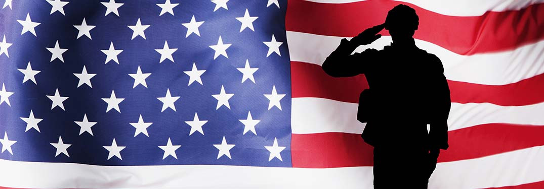 Silhouette of a soldier saluting in front of the United States flag