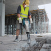 Bosch BH2770VCD Brute Turbo 15 Amp 1-1/8 inch Hex Breaker Hammer with Deluxe Cart showing in use demolishing concrete slab on a job site