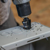 Klein Tools KTSB11 #11 2-Step 7/8 inch to 1-1/8 inch Double-Fluted High-Speed Step Drill Bit showing in use drilling into an electrical junction box Klein Tools KTSB11 #11 2-Step 7/8 inch to 1-1/8 inch Double-Fluted High-Speed Step Drill Bit showing in use drilling into an electrical junction box