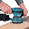 Makita BO5041K 3 Amp 5in Random Orbit Sander Kit showing in use sanding down a wood planks Makita BO5041K 3 Amp 5in Random Orbit Sander Kit showing in use sanding down a wood planks