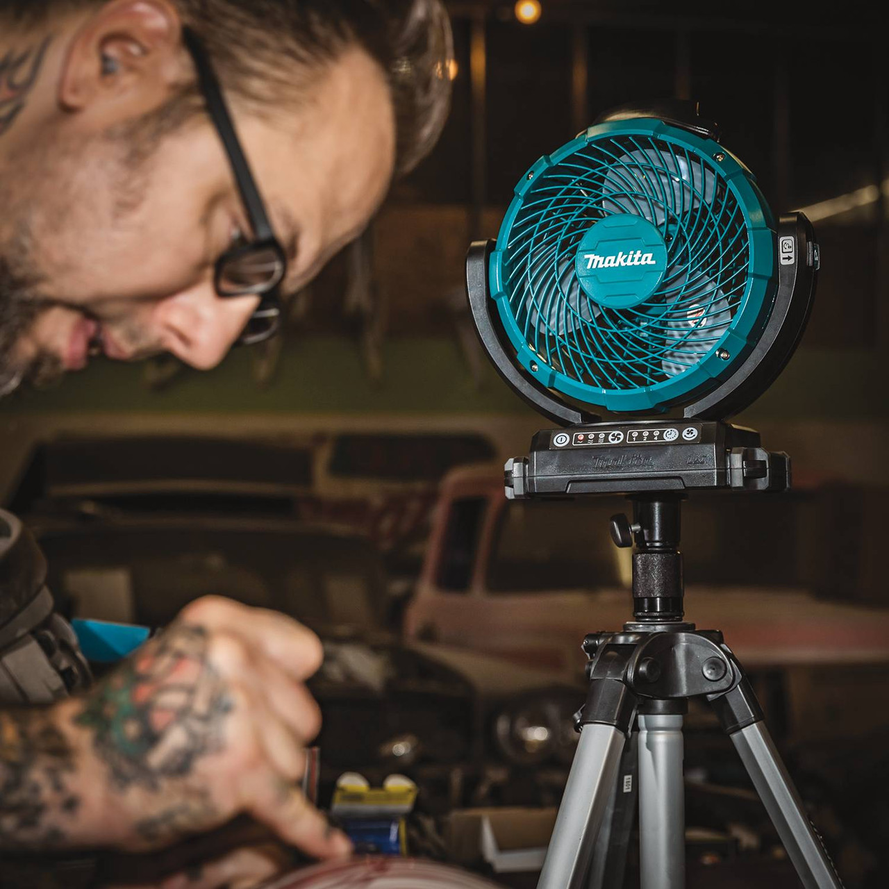 Makita DCF102Z 18V LXT Cordless 7-1/8 inch Jobsite Swing Fan (Tool Only) showing in use being pointed at a worker mounted to compatible tripod Makita DCF102Z 18V LXT Cordless 7-1/8 inch Jobsite Swing Fan (Tool Only) showing in use being pointed at a worker mounted to compatible tripod