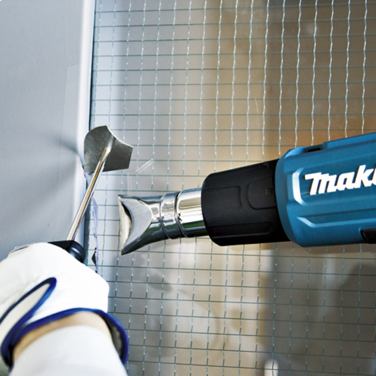 Makita HG5030K 13 Amp 2-Stage Heat Gun showing in use heating up trim in order to push it into space holding heat panels hold in place