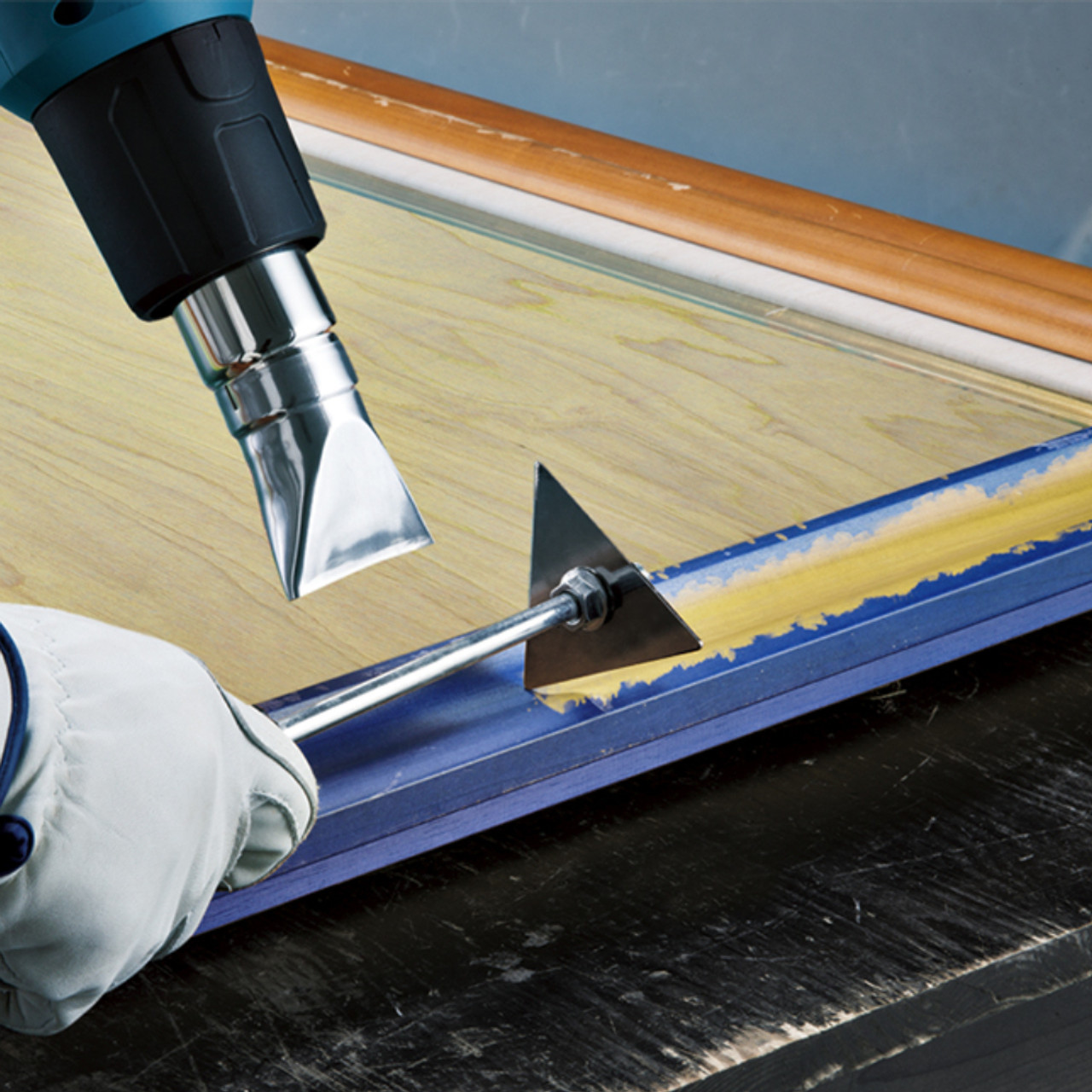 Makita HG5030K 13 Amp 2-Stage Heat Gun showing in use heating up old paint and scraping it away from the trim